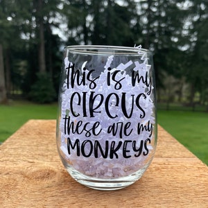 May include: A clear glass wine glass with the text "This is my circus these are my monkeys" printed in black.