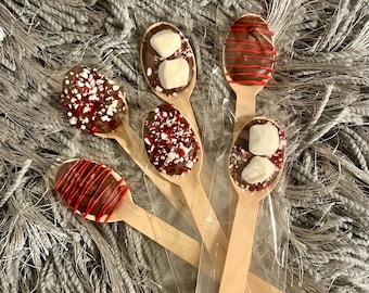 May include: Wooden spoons dipped in chocolate, decorated with red drizzle, crushed peppermint, and marshmallows. The spoons are packaged in a clear plastic bag, perfect for a sweet treat or hot cocoa.