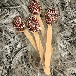 Puede incluir: Cuatro cucharas de madera con cobertura de chocolate y chispas rojas y blancas. Las cucharas est&aacute;n en una bolsa de pl&aacute;stico transparente. Fondo gris texturizado. Un dulce.