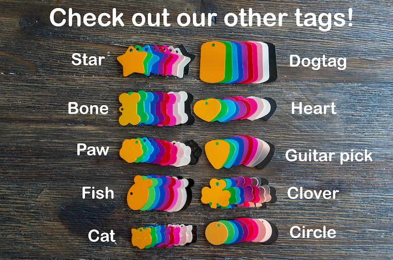 Puede incluir: Surtido de etiquetas met&aacute;licas de colores en varias formas, incluyendo estrella, hueso, pata, pez, gato, coraz&oacute;n, p&uacute;a de guitarra, tr&eacute;bol y c&iacute;rculo. Las etiquetas est&aacute;n dispuestas en filas sobre una superficie de madera. El texto "Check out our other tags!" est&aacute; en la parte superior de la imagen.