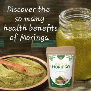 May include: A brown paper bag with a white label that says "Organic Moringa" and "100% Organic Moringa Powder". The bag is filled with green powder. There is a glass jar of green liquid and a wooden spoon with green powder in a bowl.