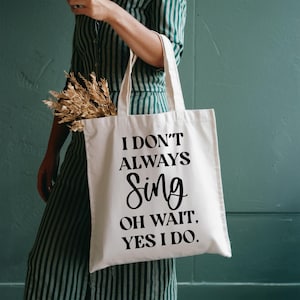 Puede incluir: Una bolsa de tela blanca con texto negro que dice "No siempre canto, oh espera, sí lo hago."