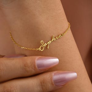 A gold chain bracelet with the name "Sophia" written in cursive script.