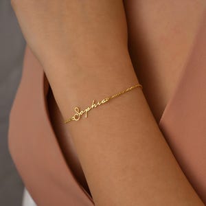 A gold chain bracelet with the name "Sophia" written in cursive script.