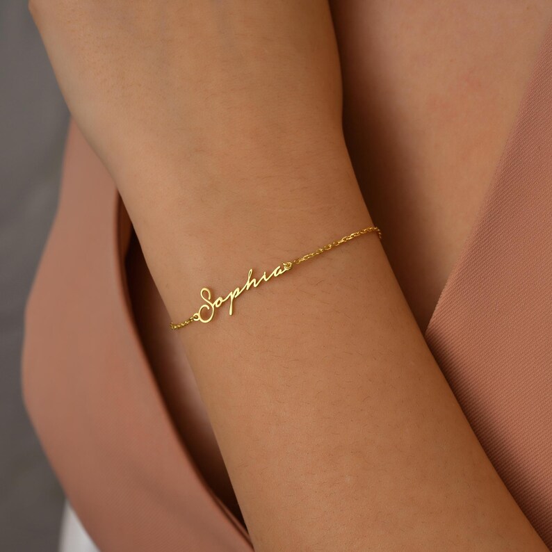 A gold chain bracelet with the name "Sophia" written in cursive script.