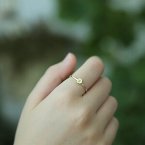 May include: A gold ring with a small round disc featuring the letter "B" engraved on it.