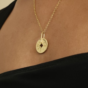 May include: A gold necklace with a round pendant featuring the letters "N, S, E, W" and numbers 1-12. The pendant is a compass design.