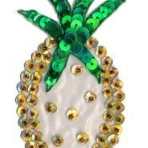May include: A white fabric pineapple with gold and green sequins. The pineapple is a decorative patch or applique.