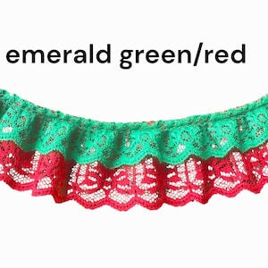 May include: Emerald green and red lace trim with a scalloped edge. The text "emerald green/red" is displayed above the trim. The lace is layered, with the green lace on top of the red lace.
