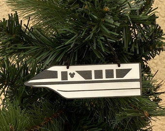 May include: A white and black Christmas ornament shaped like a Disney monorail train. The ornament has a black Mickey Mouse head on the side.