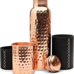 Puede incluir: Un juego de tres botellas de agua de cobre con textura martillada. Las botellas vienen con una funda de transporte de cuero negro.