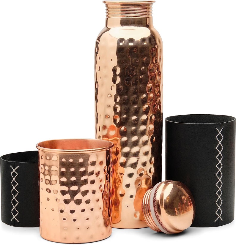 Puede incluir: Un juego de tres botellas de agua de cobre con textura martillada. Las botellas vienen con una funda de transporte de cuero negro.