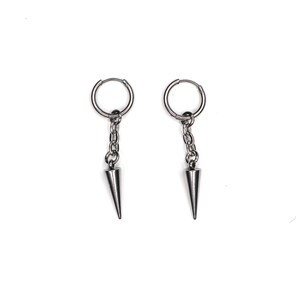 May include: A pair of silver-colored hoop earrings with a chain and a conical spike pendant. The earrings are displayed against a white background. The earrings are a simple, yet edgy accessory.
