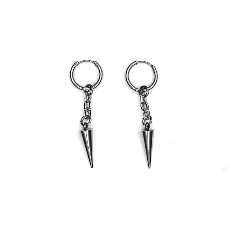 May include: A pair of silver-colored hoop earrings with a chain and a conical spike pendant. The earrings are displayed against a white background. The earrings are a simple, yet edgy accessory.