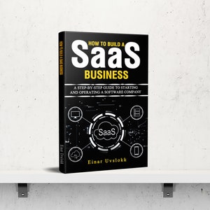 Peut inclure: Un livre intitulé "How to Build a SaaS Business" est présenté sur une étagère blanche. Le livre a une couverture noire avec du texte blanc et jaune. La couverture présente un schéma avec le mot "SaaS" au centre et le nom de l'auteur, Einar Uvslokk.