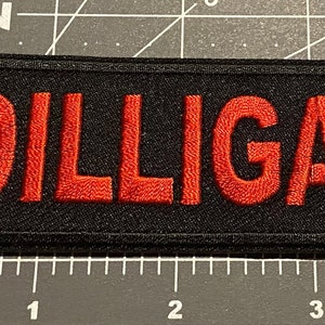 May include: A black patch with red embroidered text that reads "DILLIGAF".