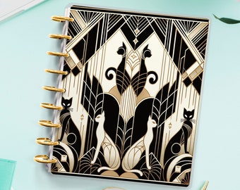Könnte beinhalten: Ein schwarzer und goldener Planer mit einem geometrischen Design mit stilisierten Katzen. Der Planer hat einen transparenten Umschlag und goldene Ringe.