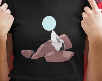 May include: Black t-shirt with a graphic of a white and brown seal balancing a blue orb on its nose on top of a pile of rocks.