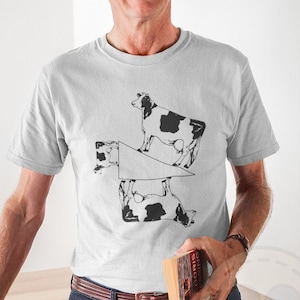 May include: A white t-shirt with a black and white graphic of four cows in a geometric pattern. The cows are arranged in a way that creates a visual illusion.