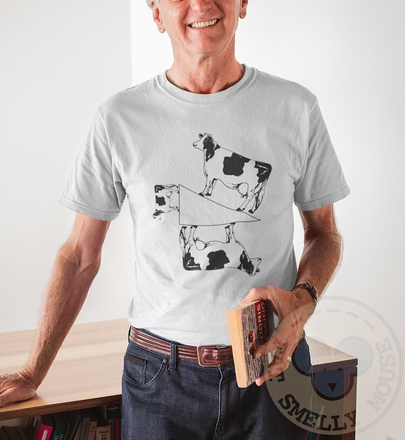 May include: A white t-shirt with a black and white graphic of four cows in a geometric pattern. The cows are arranged in a way that creates a visual illusion.