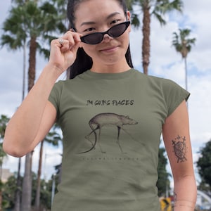 May include: A green t-shirt with a graphic of a rat with the text "I'm going places" and the artist's name "Fatimelly Mouse" printed on the front.