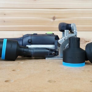 May include: A black and blue power tool with a dust collection system. The tool has a round blade and a clear plastic dust collection tube. The dust collection tube is labelled "TOOLCURVE".