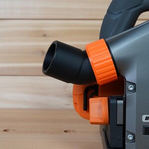 May include: A close-up of a gray and orange power tool with a black dust port and the word "BRUSHLESS" printed on the side.