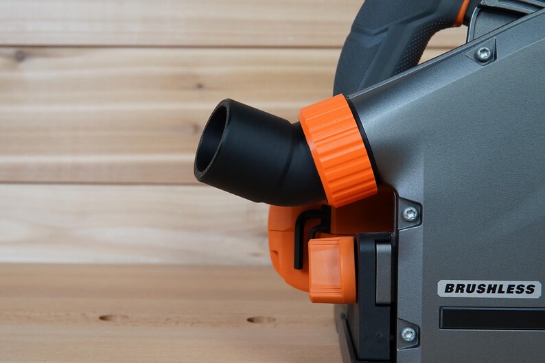 May include: A close-up of a gray and orange power tool with a black dust port and the word "BRUSHLESS" printed on the side.