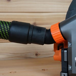 May include: A close-up of a black and orange power tool with a dust collection hose attached. The tool has a "BRUSHLESS" label on the side.