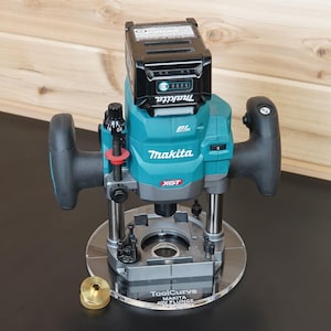 May include: A teal and black Makita plunge router with a battery pack attached, featuring a clear circular base plate with the text ToolCurve Makita 40V Plunge printed on it, accompanied by a small brass-coloured circular guide bushing component.