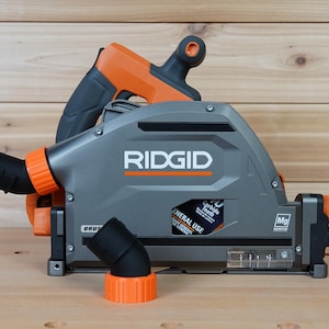 May include: A gray and orange RIDGID circular saw with a dust port and a 40 carbide tooth blade. The saw is on a wooden surface.