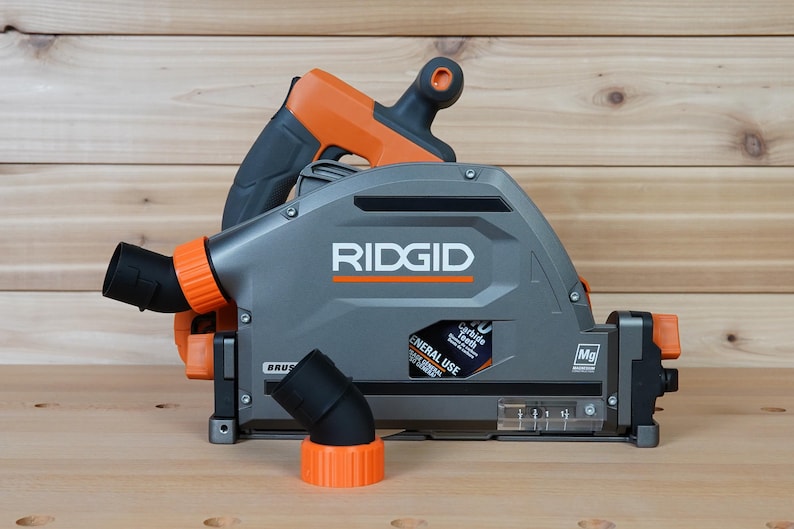 May include: A gray and orange RIDGID circular saw with a dust port and a 40 carbide tooth blade. The saw is on a wooden surface.