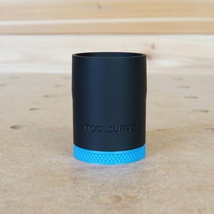 Puede incluir: Un soporte de herramientas cil&iacute;ndrico negro con una base azul texturizada. El soporte tiene el texto "TOOLCURVE" impreso en el lateral.