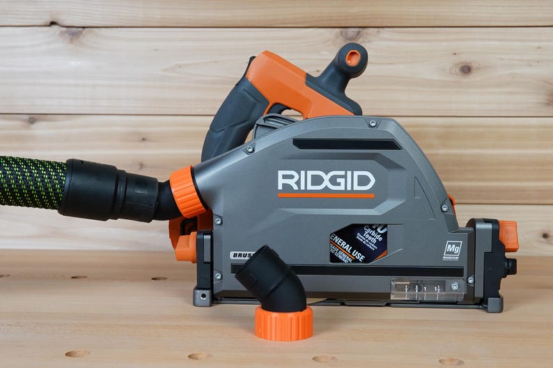 May include: A gray and orange RIDGID circular saw with a dust collection port and a 70 carbide tooth blade. The saw is on a wooden surface.