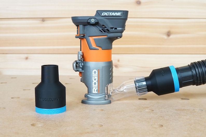 Pode incluir: Uma fresadora Ridgid preta e cinza com uma base laranja e um tubo de coleta de p&oacute; de pl&aacute;stico transparente conectado a uma mangueira de coleta de p&oacute; preta. A fresadora &eacute; etiquetada com "OCTANE" e "RIDGID".