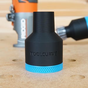 Pode incluir: Um adaptador de recolha de p&oacute; preto com uma guarni&ccedil;&atilde;o azul e o texto "TOOLCURVE" impresso no lado. O adaptador &eacute; projetado para se ajustar a uma fresadora.