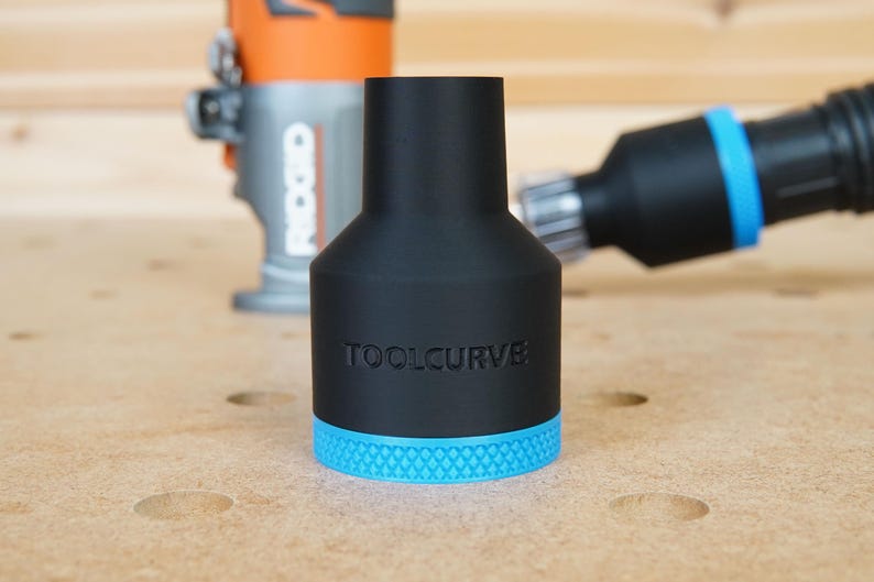 Pode incluir: Um adaptador de recolha de p&oacute; preto com uma guarni&ccedil;&atilde;o azul e o texto "TOOLCURVE" impresso no lado. O adaptador &eacute; projetado para se ajustar a uma fresadora.