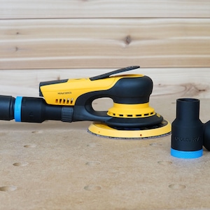 May include: A yellow and black electric sander with a dust collection hose attached. The sander has a black handle and a yellow base. Two black dust collection adapters are also shown.