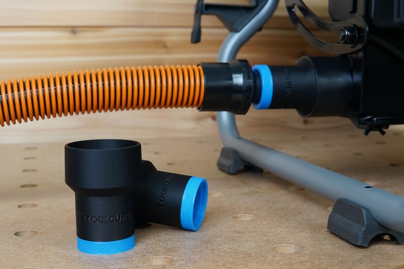 Op de afbeelding: Twee zwarte stofafzuigadapters met blauwe afwerking en de tekst "ToolCury" erop gedrukt. De adapters zijn verbonden met een zwarte en oranje slang.