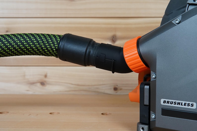 May include: A black and orange power tool with a green and black hose attached. The tool has a label that says "BRUSHLESS".