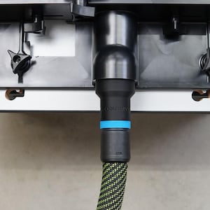 May include: A black electric vehicle charging cable with a green and black braided cord and a blue ring around the connector. The connector is plugged into a black charging port.