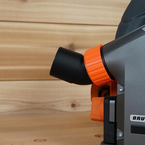 May include: Close-up of a gray and orange power tool with a black dust port and the word "BRUSHLESS" printed on the side.