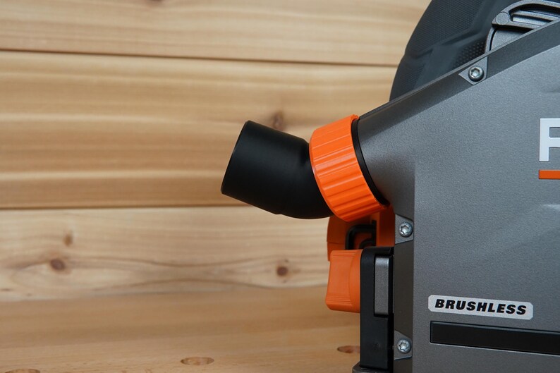 May include: Close-up of a gray and orange power tool with a black dust port and the word "BRUSHLESS" printed on the side.