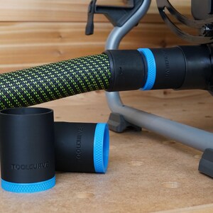 Puede incluir: Dos adaptadores de colector de polvo negros con ribete azul y el texto "TOOLCURVE" impreso en ellos. Los adaptadores est&aacute;n conectados a una manguera de polvo negra y verde.