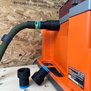 May include: A black and green dust collection hose with a black connector attached to an orange dust collector. Two black dust collection adapters are on a wooden surface.