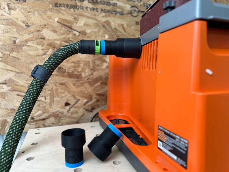 May include: A black and green dust collection hose with a black connector attached to an orange dust collector. Two black dust collection adapters are on a wooden surface.