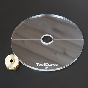 Op de afbeelding: Een doorzichtig cirkelvormig acrylsjabloon met een gat in het midden en een horizontale lijn door het midden gegraveerd. De tekst ToolCurve en 8" zijn in het wit op het oppervlak gedrukt. Een kleine, cilindrische messingkleurige metalen knop ligt links.