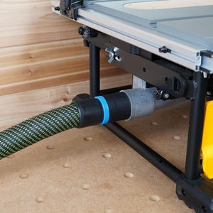 May include: A black table saw with a yellow dust collection port and a black hose connected to it. The hose is made of a black and yellow braided material.