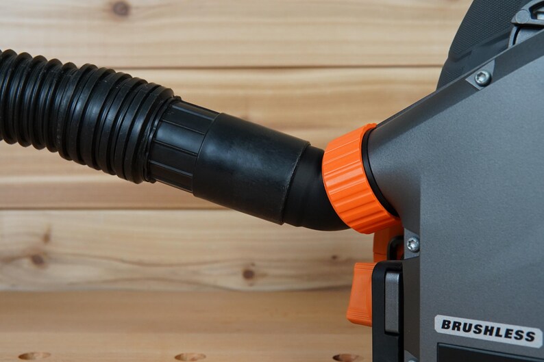 May include: Close-up of a black and orange power tool with a dust collection hose. The tool has a "BRUSHLESS" label on the side.