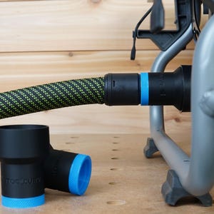 May include: A black and green hose with a blue and black connector attached to a silver metal frame. Two black and blue plastic connectors are on a wooden surface.